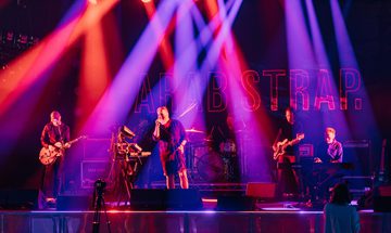 Arab Strap perform on stage under red, pink and purple spotlights