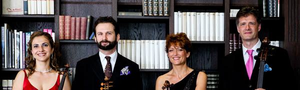 The Quartet pictured with their instruments, dressed in formalwear and standing against a library backdrop.