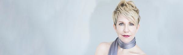 Joyce DiDonato poses stylishly, wearing a blue silk scarf