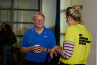 A man in a blue polo shirt holds a mug and smiles at a woman with blonde hair in a yellow Festival t-shirt