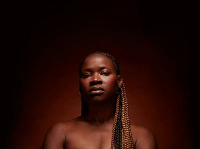 Adura Onashile looks directly at the camera with a soft halo of light behind her.