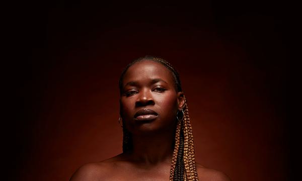 Adura Onashile looks directly at the camera with a soft halo of light behind her.