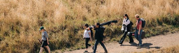 A group of people carrying instruments and filming equipment through Salisbury Crags