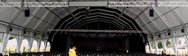 A front of house staff member in a yellow jacket prepares the Edinburgh Academy Junior School venue, surrounded by spaced-out rows of seats.