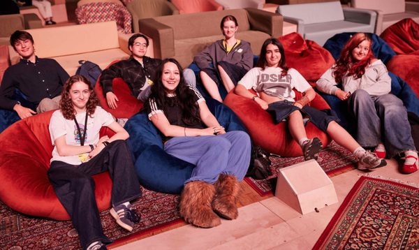 A group of teenagers sit on beanbags smiling at the camera.