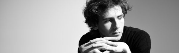 Man leaning on table, hands entwined and looking off camera