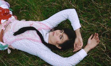 A women is lying on some grass looking up at the camera