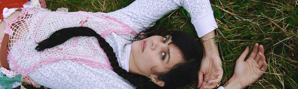 A women is lying on some grass looking up at the camera