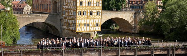 Large group of people standing together on bridge over river