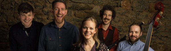 Group of musicians facing camera smiling and holding instruments