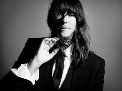 Woman with hair blowing over face wearing suit looking at camera