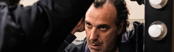 A man is standing in front of a mirror looking at himself as he touches his hair