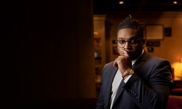 Man wearing suit resting his hand on mouth and facing the camera