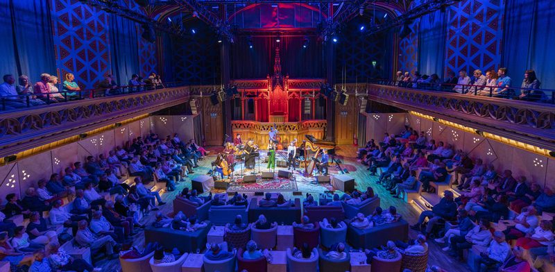 Stringed musicians performing to an audience in large theatre