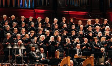 Large female choir singing above orchestra musicians