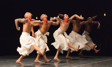 5 men dancing on stage arms and legs out stretched facing upwards