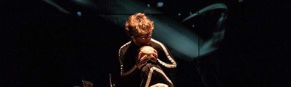 Man crouched on stage holding skull
