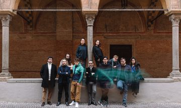 Group of men and women standing by arched pillared wall