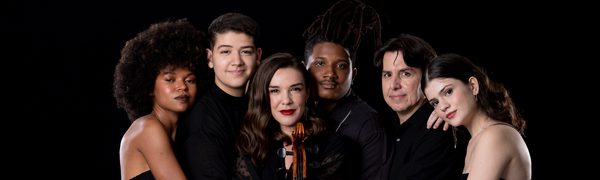 Woman holds stringed instrument people gathered around her with arms entwined