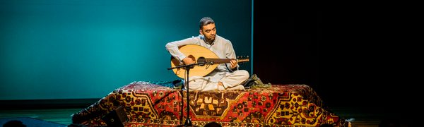 a man sits on a persian rug playing a stringed instrument