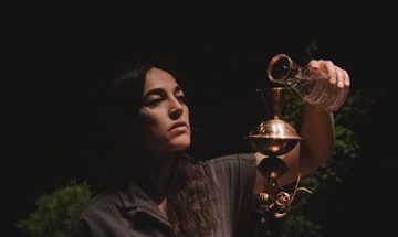Woman pours liquid in to an ornate metal container