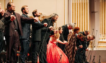 Group of people on a stage, hands linked and taking a bow