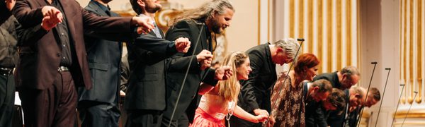 Group of people on a stage, hands linked and taking a bow