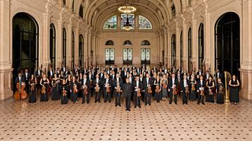 Symphony Orchestra standing together in grand hall holding their instruments