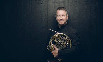 Man standing holding wind instrument