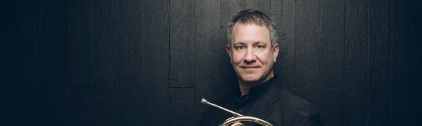 Man standing holding wind instrument