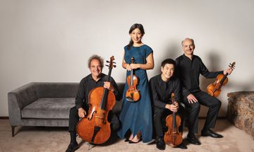 Four string-players smile at the camera