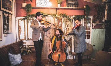 Three men playing stringed instruments in room