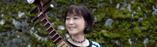 Woman looking off camera holding a stringed instrument