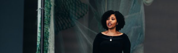 Woman wearing long black dress singing looking off camera