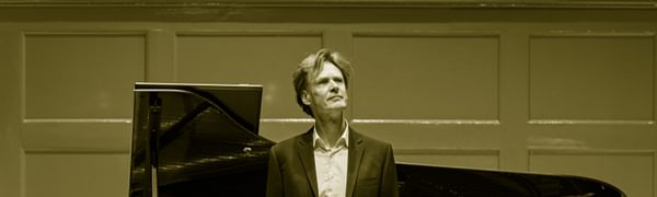 A man stands in front of a grand piano
