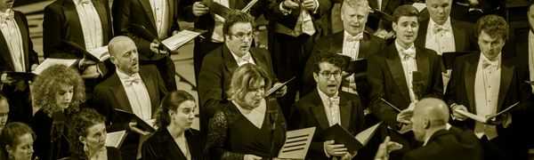 A choir dressed in formal wear sings in front of their conductor.