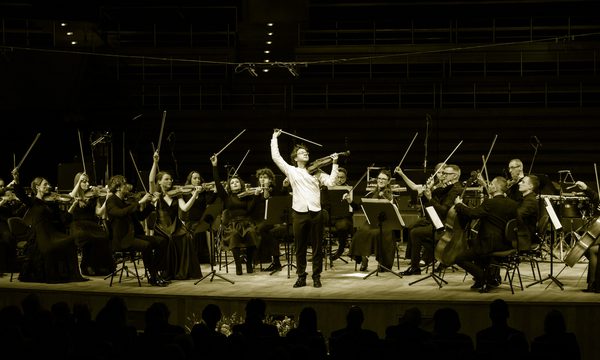 a group of string players flourish their bows in the air