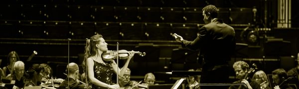 A woman stands on stage playing a violin
