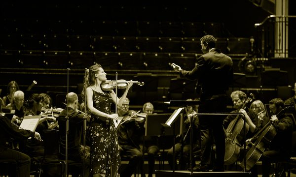 A woman stands on stage playing a violin