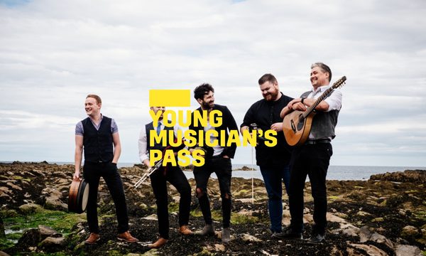 A yellow logo reading Young Musician's Pass overlays a group of five musicians standing on a rocky landscape with the sea behind them. They are laughing and smiling while holding instruments.