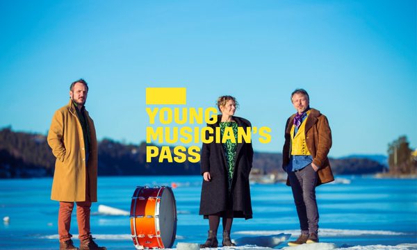 A yellow logo reading Young Musician's Pass overlays three musicians standing on a snowy landscape with a bright blue sky. They are dressed in bright colours with a drum sitting next to them.