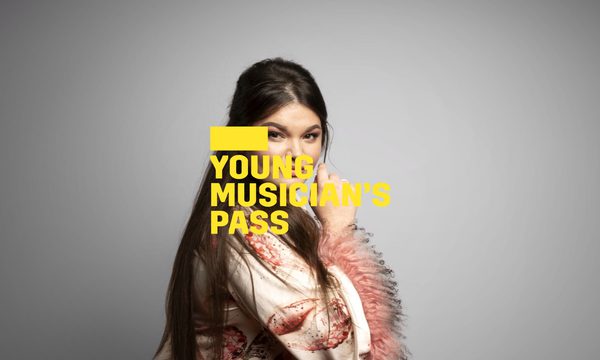 A yellow logo reading Young Musician's Pass overlays a woman with long brown hair in a pink and white gown looking over her shoulder with a knowing smile