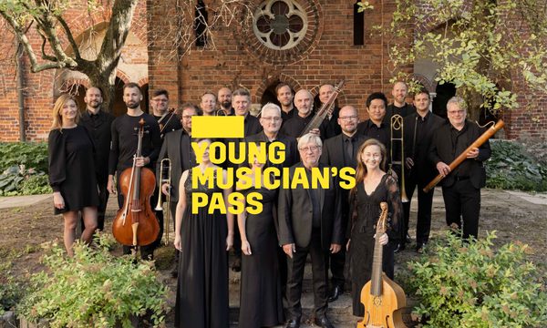 A yellow logo reading Young Musician's Pass overlays a group of musicians dressed in black standing in front of a brick building. Trees and bushes frame them.