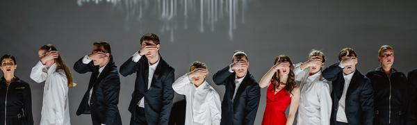 a row of people stand with there hands over their eyes