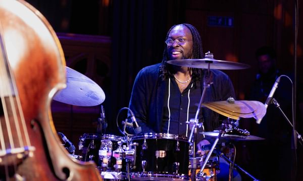 A drummer smiles at someone out of view