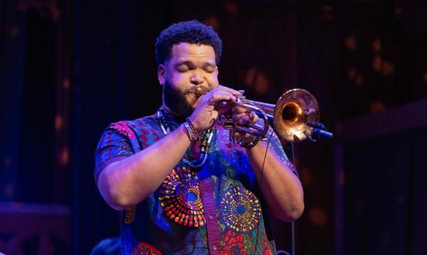 A man plays the trumpet with his eyes closed