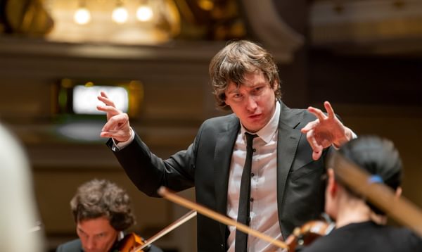 A young conductor makes pinching motions with both hands
