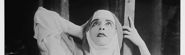 Black and white theatrical image of a nun looking up at the sky