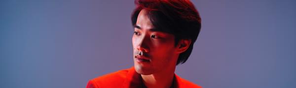 A man in a suit looks off to one side, he is bathed in red light