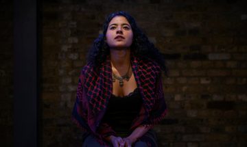 A person sits on stage looking off into the distance